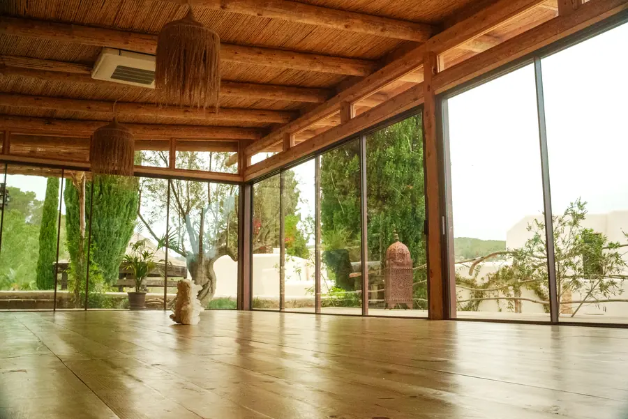 Leeres Studio mit Holzboden, Holzdecke und Glasfront zum Grün